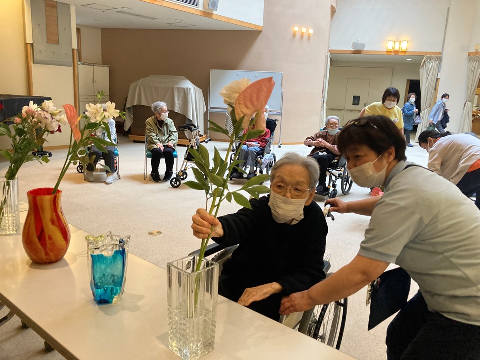 聖母月の5月31日、聖母ホームではマリア祭が行われました。<br>5月は四季折々の中で春の訪れとともに緑が眩しい季節です。<br>1階のホールにご利用者が集まり、みんなでお花を捧げました。<br><br>施設長からは、「世界各地で猛威を振るう新型コロナウイルスが<br>少しでも早く収束しますように、そして世界平和のため、<br>また病床にある人たちにいやしが与えられますように<br>みんなでお祈りをしましょう」とお話がありました。<br>