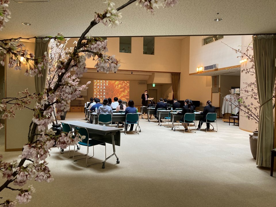 先輩の職員から<br>私は30歳の時一旦故郷に帰りましたが、いろいろな刺激を受けたいと思いケアマネの資格を取って聖母ホームに入職しました。<br>当時はネットがなかったので、遠くから何回も通って東社協の求人を見て応募しました。<br><br>そして20年間ご利用者からいろいろな事を学びました。街並みを見るといろいろな家が建っていますが、中に入ると様々な相談事が寄せられ、物事はなかなか順風満帆にはいかないということを知らされます。<br><br>一歩づつ歩んでいかねばなりません。私はクリスチャンなので「主」を信じてやっています。<br>みなさんも可能性の哲学を持っていただき、どんなことがあっても必ず好転していくことを信じて行って欲しいです。<br><br>我々が生き生きと仕事していないと、ご利用者も楽しく生活することができません。<br>私も聖母ホームに招かれました。介護は辛い思いをすることもありますが、お互い支え合ってやっていきましょう。<br><br>ホームにとってかけがえのない新人職員のみなさん、これからどうぞよろしくお願いいたします。<br>
